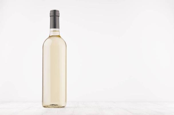 Transparent wine bottle with white wine on white wooden board, mock up.  - Zdjęcie, obraz
