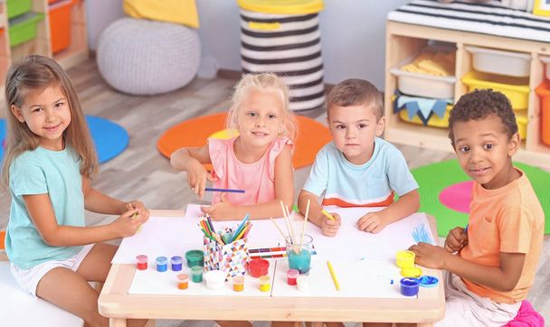 Lindos niños pintando en la mesa interior
 - Foto, Imagen