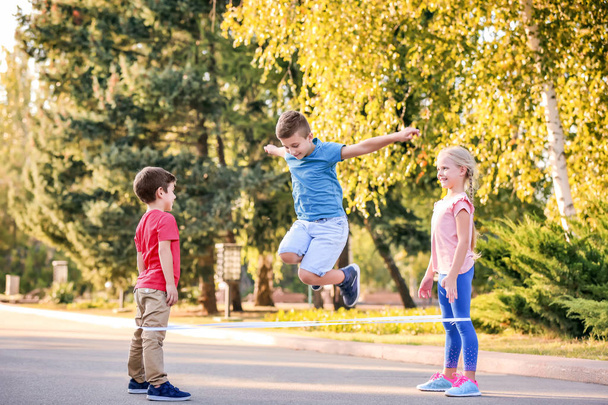 Adorable children playing elastic game outdoors - Fotoğraf, Görsel