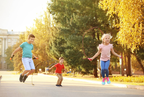 Adorable children skipping rope outdoors - Zdjęcie, obraz