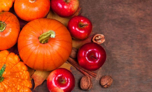 Осенний тыквенный День Благодарения фон с апельсиновыми тыквами, яблоками и опавшими листьями на деревянной доске
 - Фото, изображение