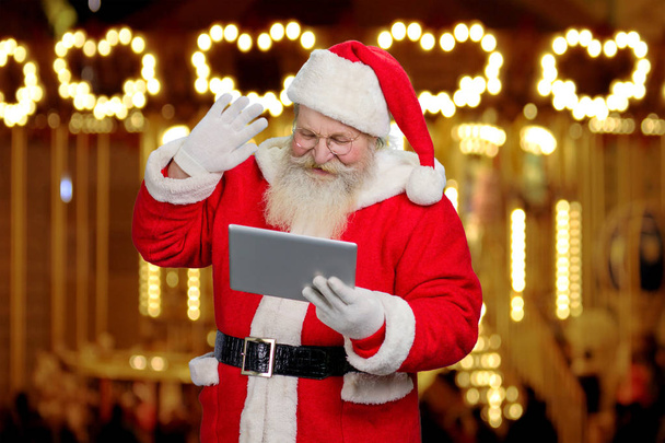 Санта-Клаус жестикулирует с помощью планшета
. - Фото, изображение