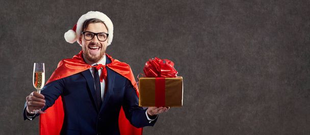 Businessman in a Santa Claus costume, a superhero with a glass o - Photo, image