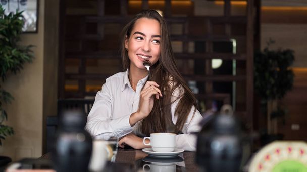Érzéki fiatal üzleti nő grinkig tea a kávézóban. Szexi mosolyogva és flörtöl - Fotó, kép