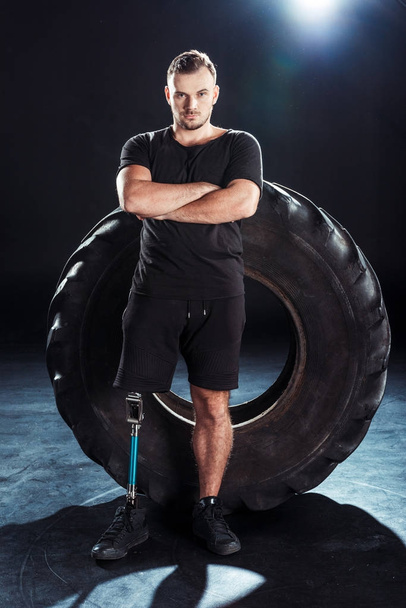 Паралимпийский спортсмен опирается на шины
 - Фото, изображение