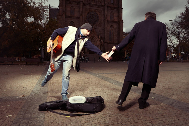 Unknown man stealing money to beggar with guitar - Foto, Imagem