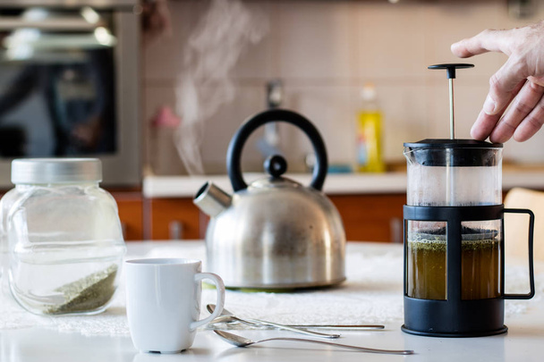 Morning yerba tea. Tasty tea brewed in cafetiere on the kitchen  - Photo, image