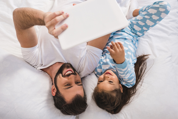 father and daughter using tablet in bed - Photo, Image