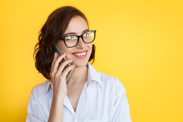 Woman in glasses smiling talking on phone - Foto, imagen