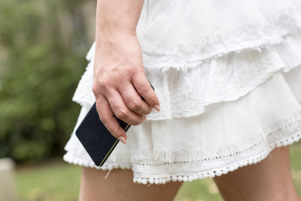 Young woman in white skirt with mobile phone in her hand - Valokuva, kuva