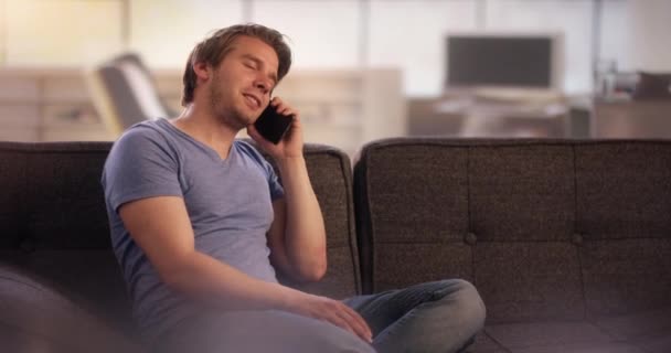 Young man on couch having a funny telephone call - Séquence, vidéo