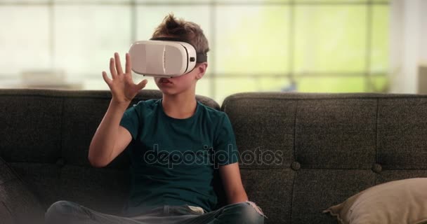 Boy using virtual reality headset on the couch - Felvétel, videó