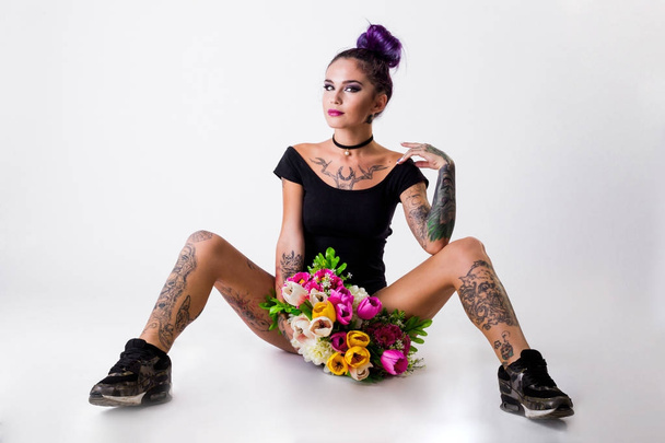 Hermosa mujer joven con el pelo carmesí elegante y tatuaje en su cuerpo posando sobre fondo grunge oscuro. Colorante capilar. Cosméticos, maquillaje. Tatuaje
. - Foto, imagen
