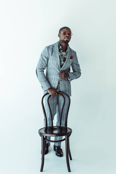 man in fashionable suit posing with chair - Foto, Imagen