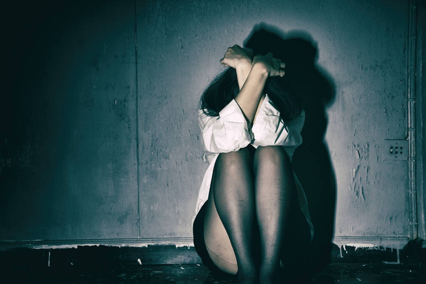 Przygnębiony i sfrustrowany, smutna kobieta siedzi w ciemnym pokoju, koncepcja zdrowia psychicznego. - Zdjęcie, obraz
