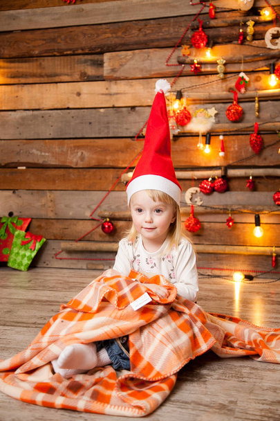 Little girl in a Christmas cap on a New Year's background - Foto, Imagen