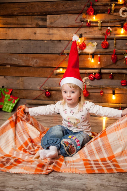Little girl in a Christmas cap on a New Year's background - Foto, Bild