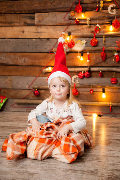 Little girl in a Christmas cap on a New Year's background - Fotoğraf, Görsel