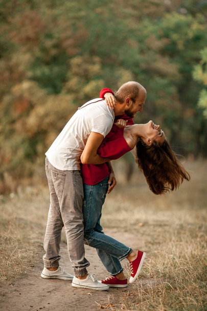 Joven pareja enamorada abraza y ríe alegremente en el descanso en el bosque
. - Foto, imagen
