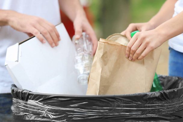 Young couple throwing garbage into litter bin outdoors, closeup - Photo, image