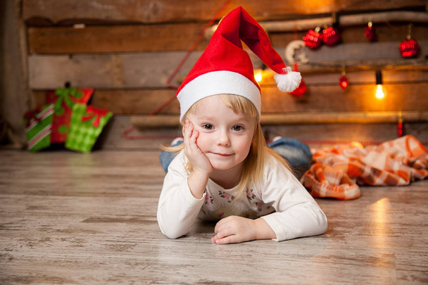 Μικρό κορίτσι σε ένα χριστουγεννιάτικο πώμα σε φόντο ενός νέου έτους - Φωτογραφία, εικόνα