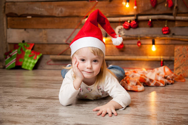 Little girl in a Christmas cap on a New Year's background - Фото, зображення