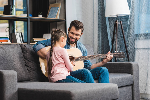 father learning daughter to play guitar - Фото, изображение