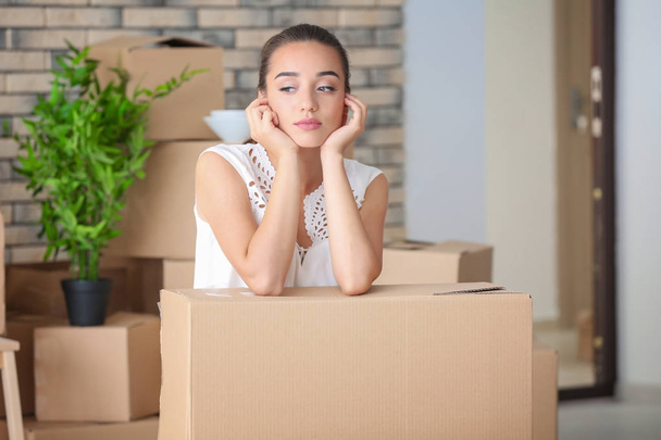 Tired young woman with moving box in her new apartment - Foto, imagen