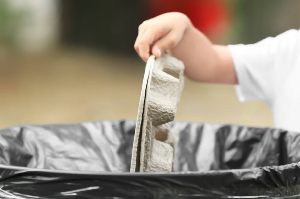 Hand of child throwing garbage into litter bin outdoors - Photo, image