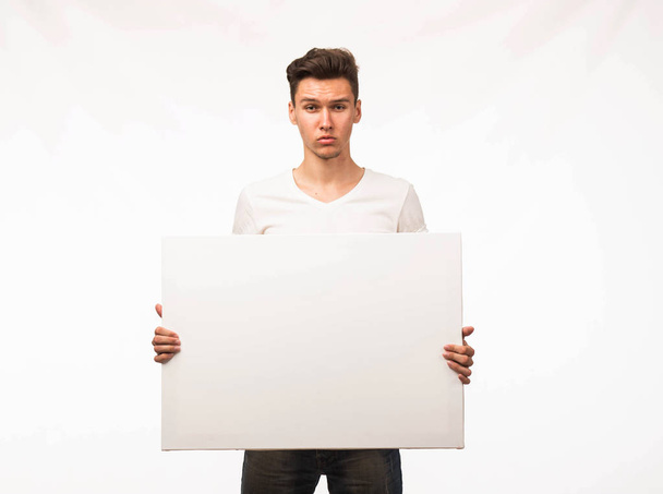 Young serious man showing presentation, pointing on placard. - Foto, immagini