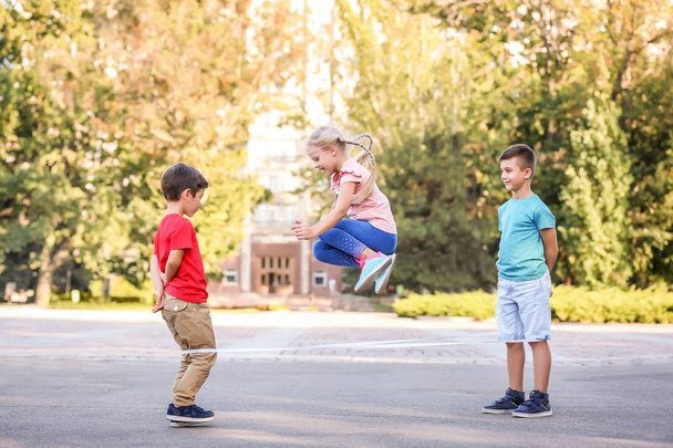 Adorable children playing elastic game outdoors - 写真・画像