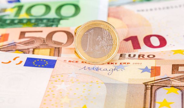 Monedas en euros sobre billetes en euros en primer plano
 - Foto, imagen