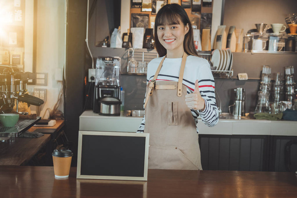 Asian barista standing at counter bar and hand showing thumb up. - 写真・画像