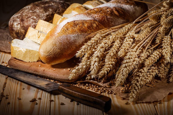 Assortment of baked bread on wooden table background - Fotó, kép