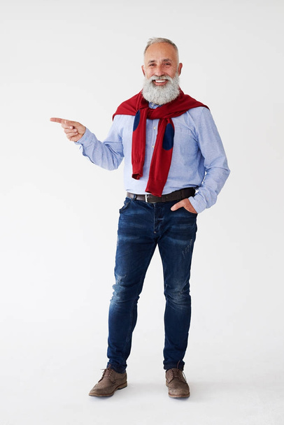 Улыбающийся взрослый бородатый мужчина указывает на копировальное пространство
 - Фото, изображение