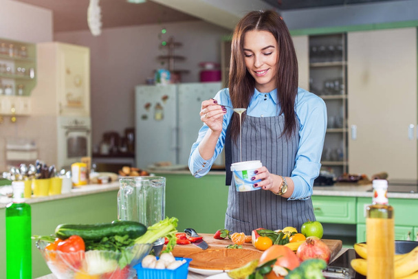 Iloinen nuori naiskokki ruoanlaitto jälkiruoka lisäämällä maitotiivistettä lautasen hänen keittiössä
 - Valokuva, kuva
