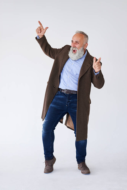 Pěkný starší vousatý v kabát zvyšování rukou ve studiu  - Fotografie, Obrázek