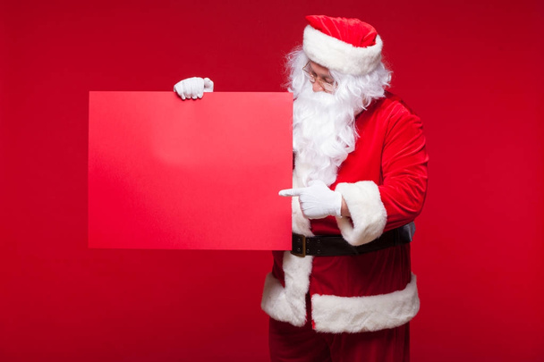Santa Claus pointing in blank advertisement banner isolated on red background with copy space red leaf - Foto, Imagem