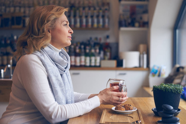 Iloinen kypsä nainen kupin teetä istuu kahvilassa
 - Valokuva, kuva