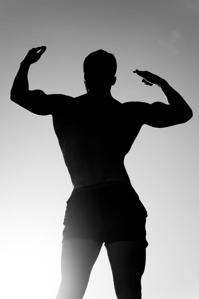 Athlete showing muscular body in dusk, back view - Фото, изображение