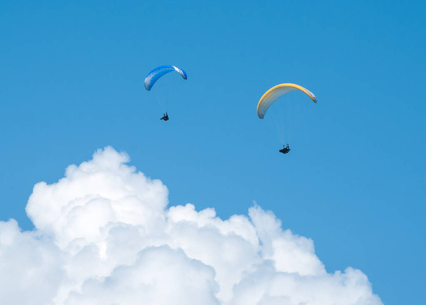 Dois parapentes voando no céu azul contra o fundo das nuvens
. - Foto, Imagem