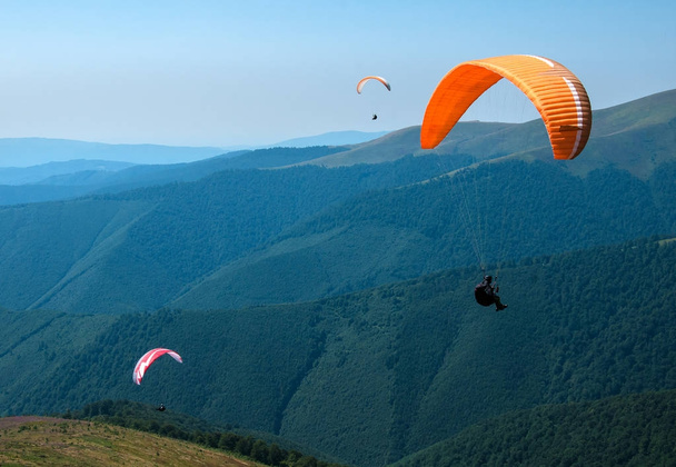 ウクライナのカルパチア山脈における夏の晴れた日の山谷上空 3 パラグライダー. - 写真・画像