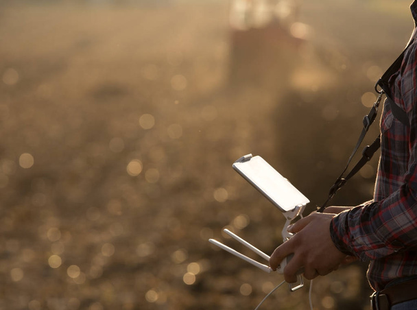 Landwirt navigiert Drohne über Ackerland - Foto, Bild