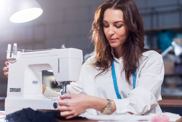 Giovane stilista donna che lavora sulla macchina da cucire in un laboratorio
 - Foto, immagini