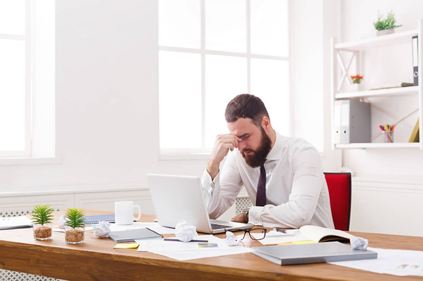 Hombre de negocios estresado con portátil en la oficina blanca moderna
 - Foto, imagen