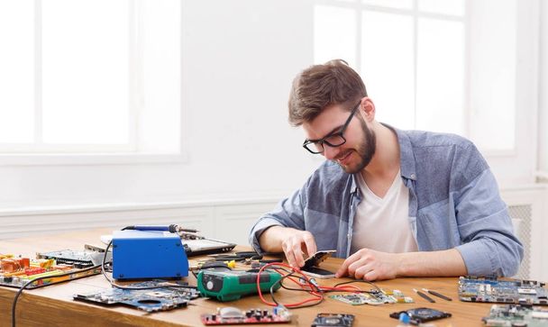 Hombre desmontaje de teléfonos inteligentes en taller de reparación
 - Foto, imagen