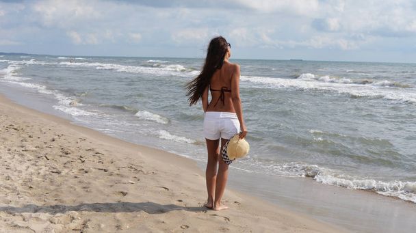 beautiful girl on the beach with a hat - Zdjęcie, obraz