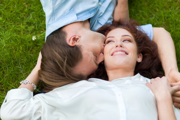 Couple in love lying down on grass - Фото, изображение
