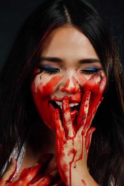 close-up portrait of a young, beautiful Asian girl on Halloween. woman covering her face bloody hand. - Fotó, kép