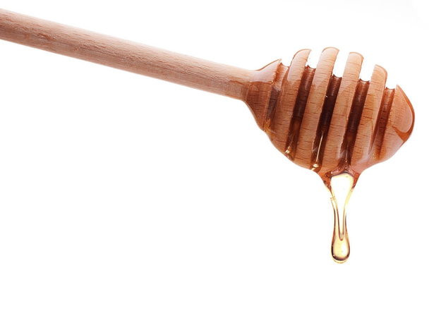 Honey dripping from wooden honey dipper  - Фото, зображення